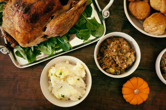Roast turkey on a platter with sides of mashed potatoes and stuffing